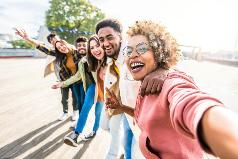 Multiracial friends group taking selfie pic with smartphone outside